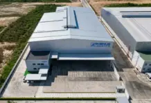 Rhenus Opens New Dangerous Goods Warehouse in Thailand Aerial view of a RHENUS Logistics warehouse with loading docks and a paved yard area.”