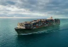 Expanding Decarbonization Ties for Ocean Freight Customers Large container ship sailing in calm blue sea under a cloudy sky, stacked with colorful cargo containers.