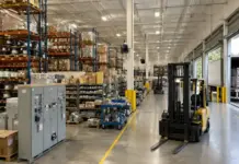 Eyeing Expansion, Graybar to Buy Samson Electrical Supply Warehouse interior with tall racks and pallets; a yellow forklift sits by the loading bays with a truck outside visible through the open dock doors.